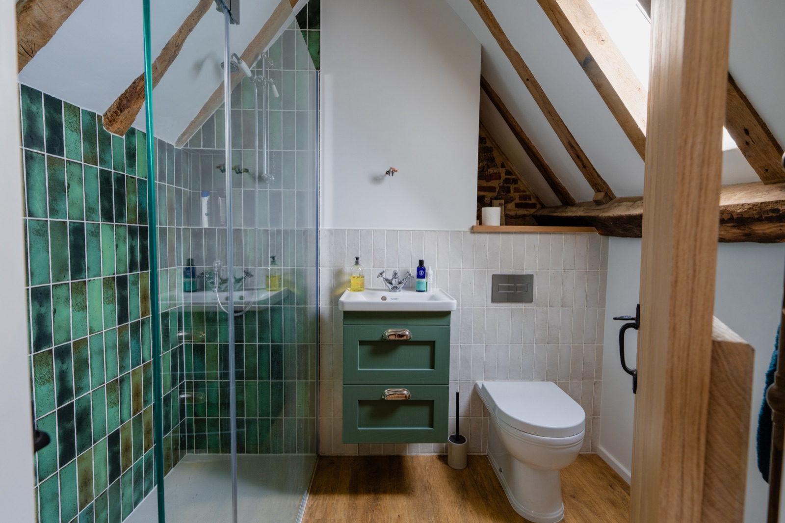 New loft en-suite with green tiled shower under exposed oak beams