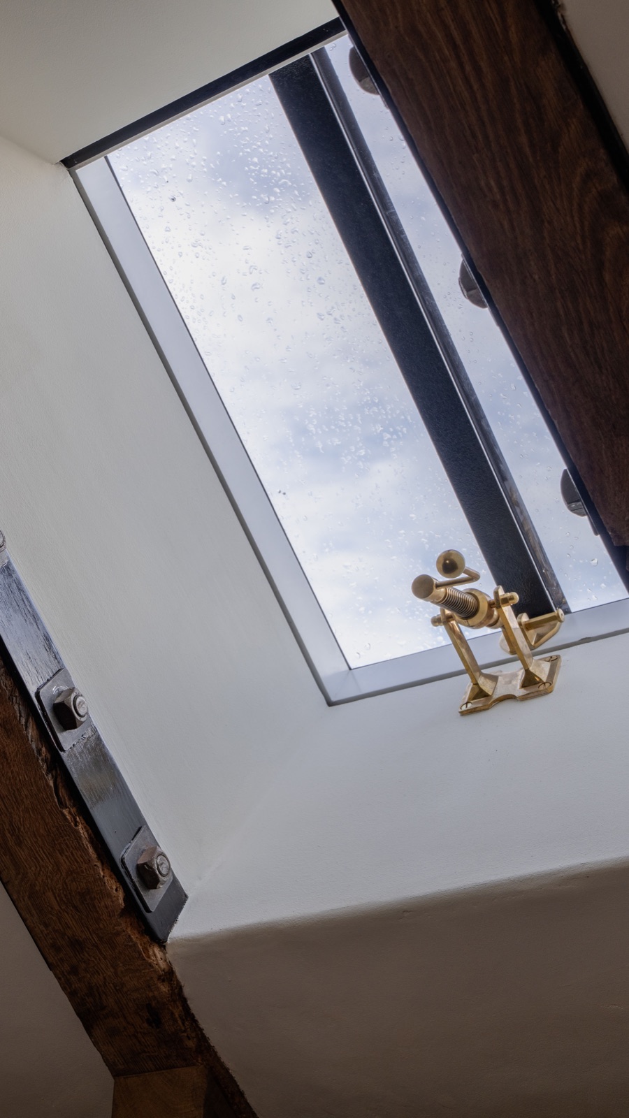 Rooflight set into the sloped loft ceiling with brass fittings